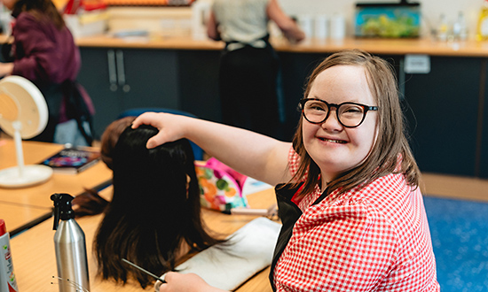 Smiling girl looking towards camera whilst holding a wig