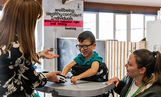  Bachgen ifanc yn gwenu gydag oedolion