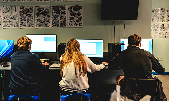 Tri disgybl yn gweithio ar gyfrifiaduron