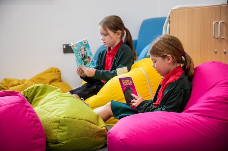 Two young girls sitting on beanbags and reading
